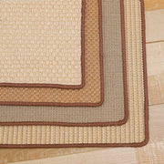 Stack of durable sisal cat scratch mats in natural tones with brown edges on a wooden floor